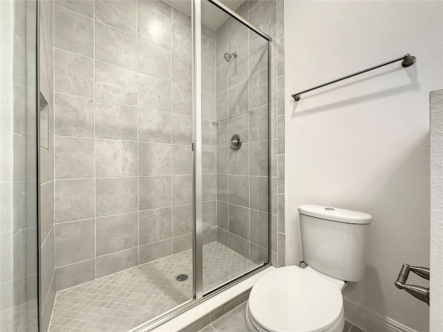 bathroom featuring a shower with door and toilet