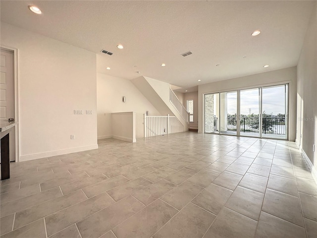 unfurnished living room with a textured ceiling and light tile patterned flooring