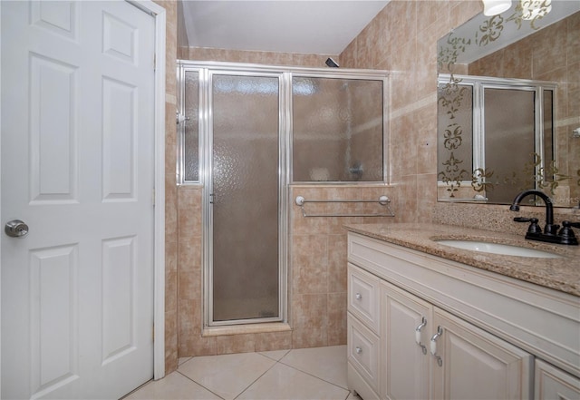 bathroom featuring tile patterned flooring, vanity, a shower with door, and tile walls