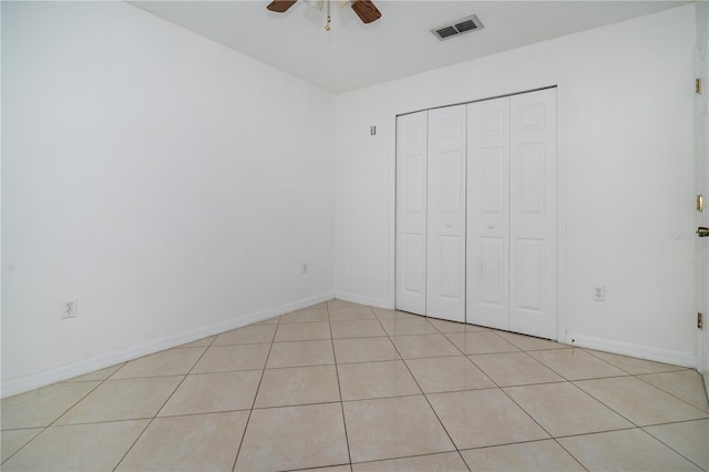 unfurnished bedroom with ceiling fan, light tile patterned floors, and a closet