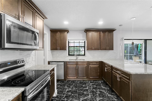 kitchen featuring appliances with stainless steel finishes, sink, backsplash, hanging light fixtures, and light stone counters