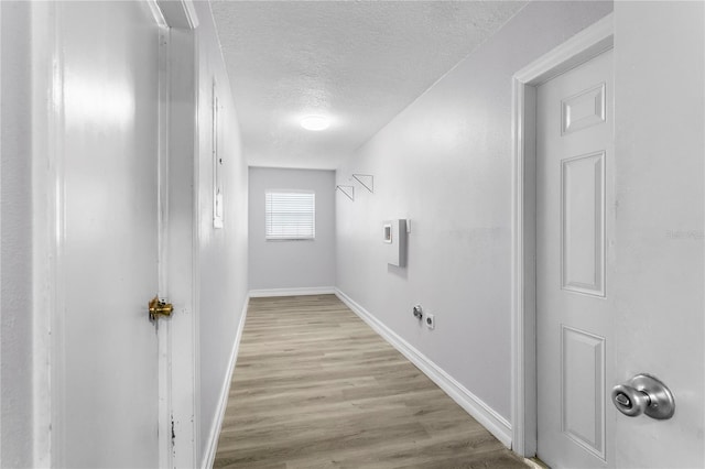 interior space featuring electric dryer hookup, a textured ceiling, and light wood-type flooring