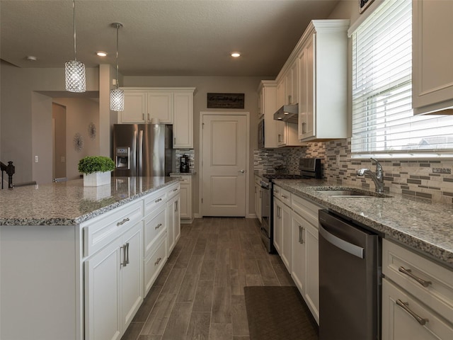 kitchen with light stone counters, white cabinets, decorative light fixtures, and appliances with stainless steel finishes