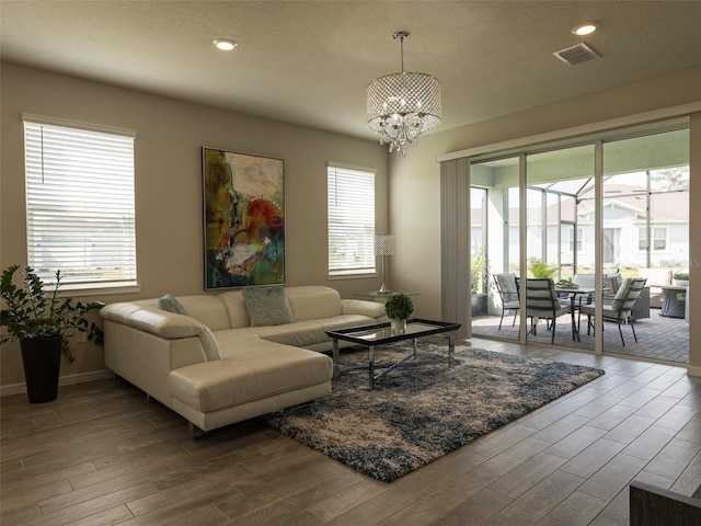 living room featuring hardwood / wood-style floors, a textured ceiling, and an inviting chandelier