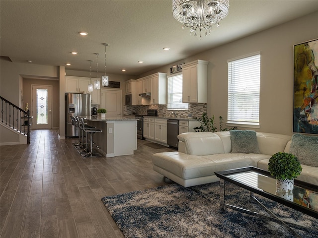 living room featuring a chandelier, a textured ceiling, and dark wood-type flooring