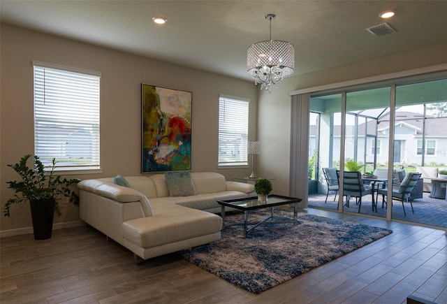 living room featuring plenty of natural light, hardwood / wood-style floors, and an inviting chandelier