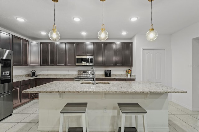 kitchen with a center island with sink, hanging light fixtures, and appliances with stainless steel finishes