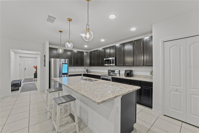 kitchen with light stone countertops, a kitchen bar, stainless steel appliances, sink, and pendant lighting