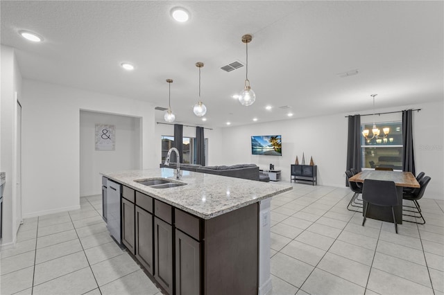 kitchen with dark brown cabinetry, light stone counters, sink, and decorative light fixtures