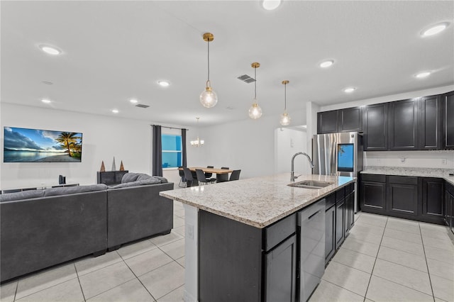 kitchen featuring light stone countertops, sink, hanging light fixtures, stainless steel appliances, and a kitchen island with sink