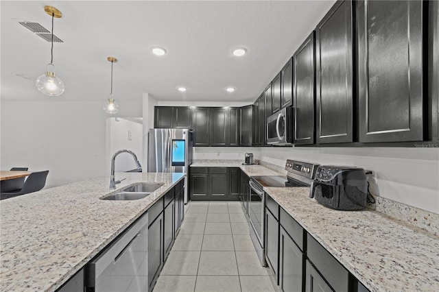 kitchen featuring light stone countertops, stainless steel appliances, sink, decorative light fixtures, and light tile patterned flooring