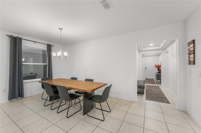 dining space with a notable chandelier, light tile patterned floors, and a tray ceiling