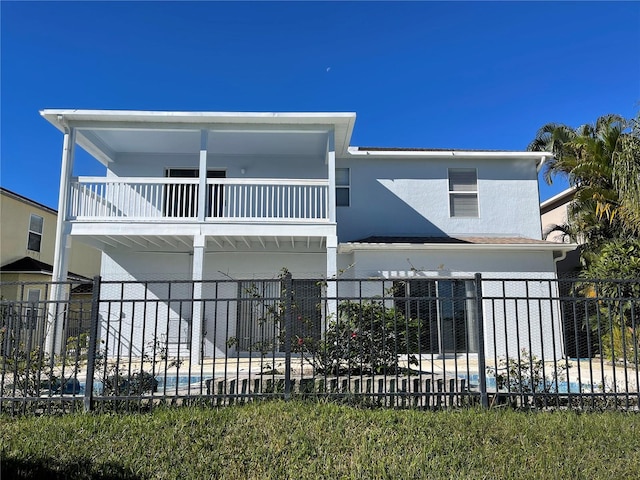 view of front of home featuring stucco siding, a balcony, and fence