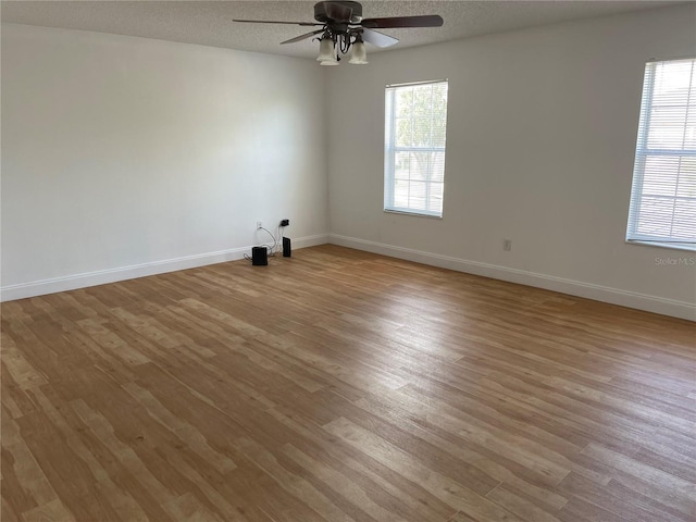 unfurnished room featuring baseboards, a textured ceiling, wood finished floors, and a ceiling fan