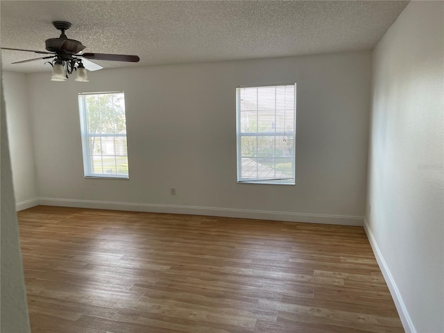 empty room featuring a ceiling fan, wood finished floors, baseboards, and a textured ceiling