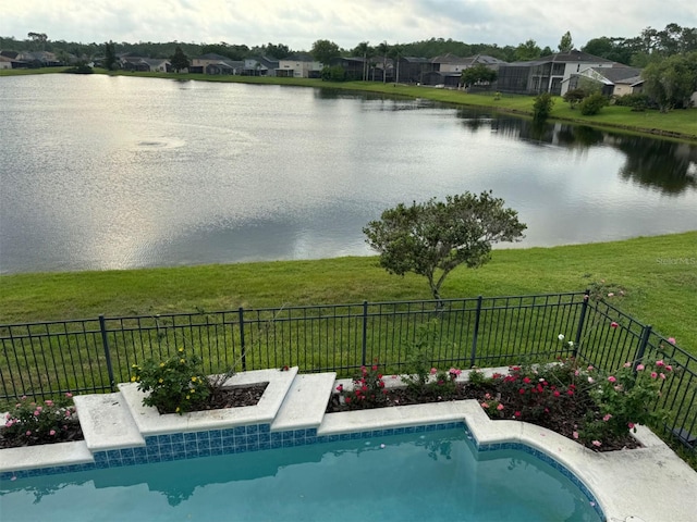 view of pool with fence, a yard, and a water view