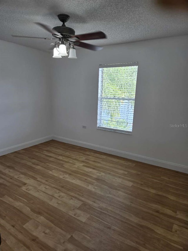 spare room featuring a ceiling fan, wood finished floors, baseboards, and a textured ceiling