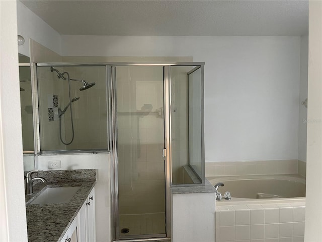 full bath with a garden tub, vanity, a shower stall, and a textured ceiling