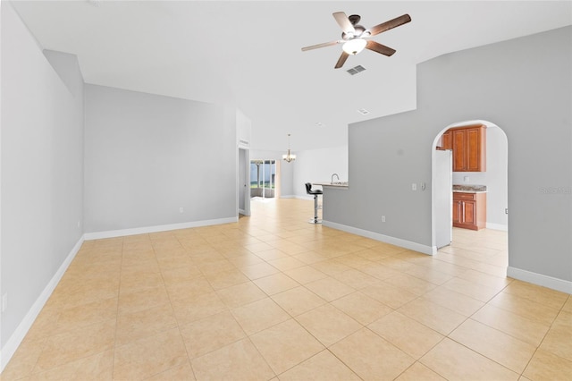 tiled spare room featuring ceiling fan with notable chandelier