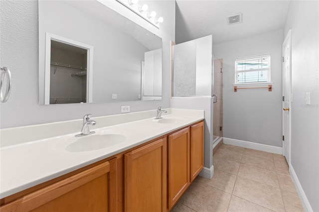 bathroom with tile patterned flooring, vanity, and walk in shower