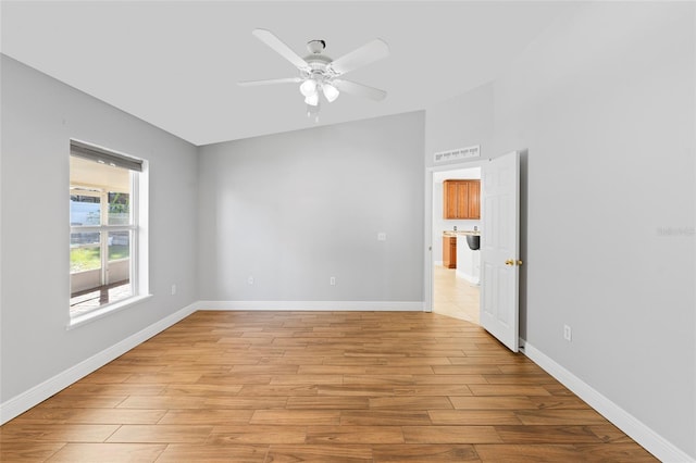 spare room featuring ceiling fan, light wood-type flooring, and lofted ceiling