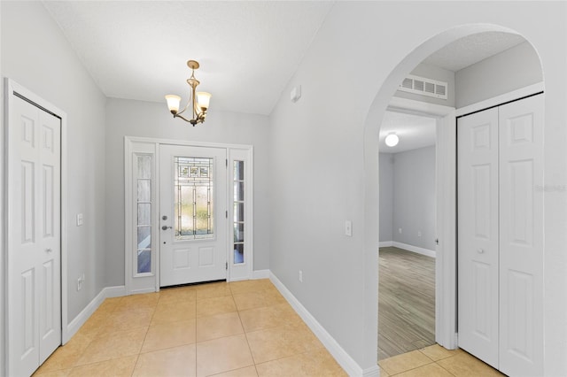 entrance foyer featuring light tile patterned floors, a textured ceiling, and an inviting chandelier