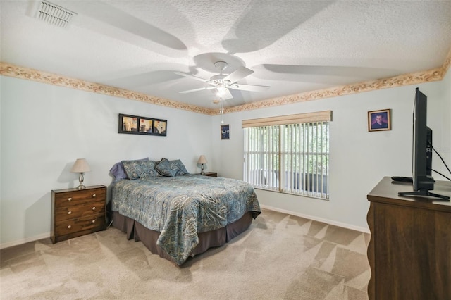 bedroom with a textured ceiling, light colored carpet, and ceiling fan