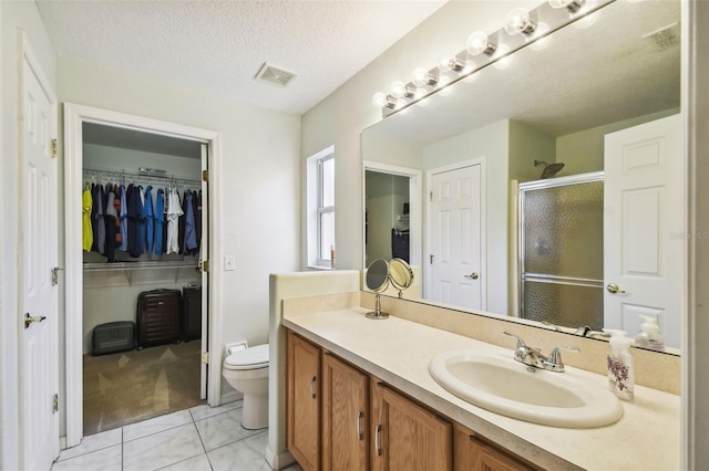 bathroom with tile patterned floors, walk in shower, vanity, a textured ceiling, and toilet