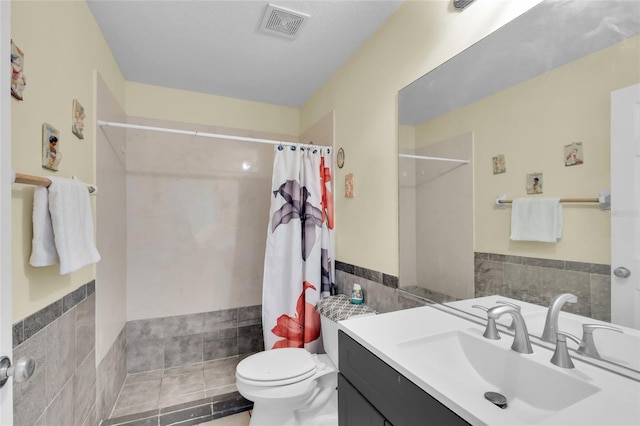 bathroom with a shower with curtain, vanity, toilet, and tile walls