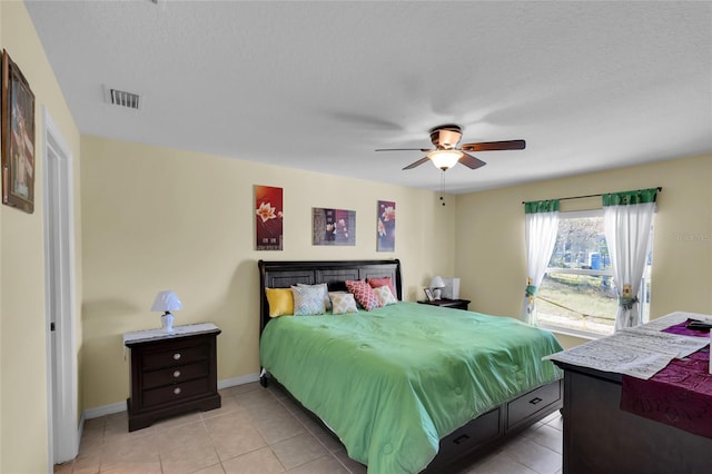 bedroom featuring ceiling fan, light tile patterned floors, and a textured ceiling