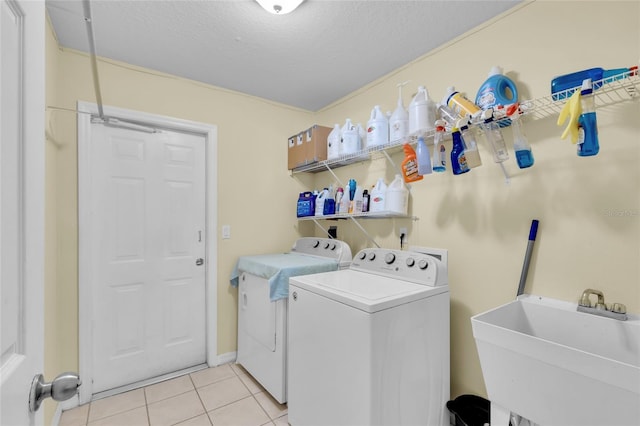 laundry area featuring a textured ceiling, washer and dryer, light tile patterned flooring, and sink