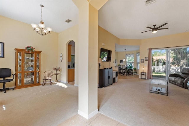 carpeted living room with ceiling fan with notable chandelier