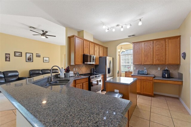 kitchen with sink, tasteful backsplash, kitchen peninsula, a kitchen island, and appliances with stainless steel finishes