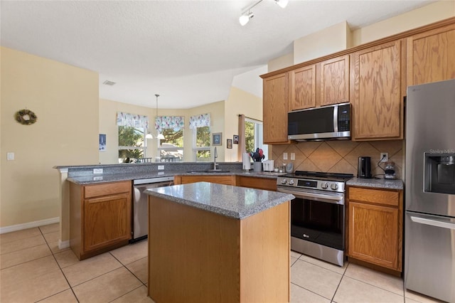 kitchen with a kitchen island, light tile patterned flooring, kitchen peninsula, and stainless steel appliances