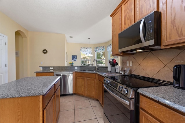 kitchen with sink, backsplash, a chandelier, light tile patterned flooring, and appliances with stainless steel finishes