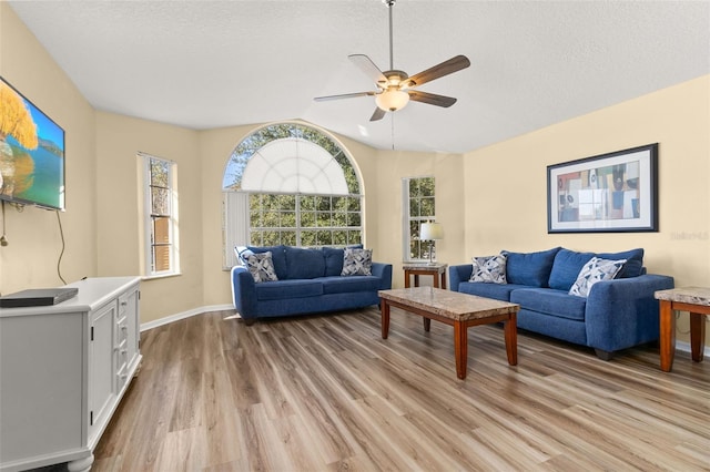 living room with a textured ceiling, light hardwood / wood-style flooring, ceiling fan, and lofted ceiling