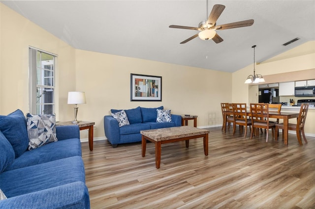 living room featuring hardwood / wood-style floors, ceiling fan with notable chandelier, and lofted ceiling