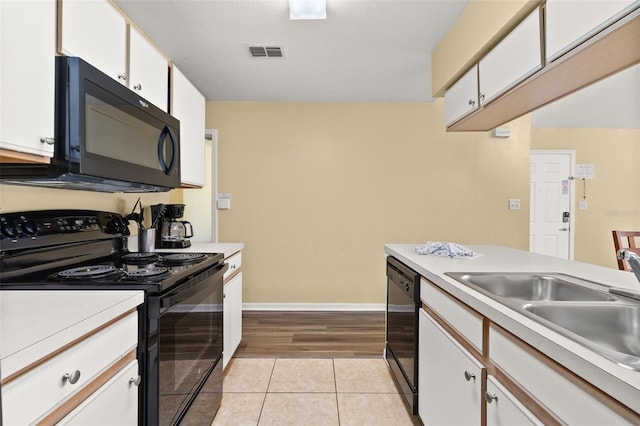 kitchen with white cabinets, light hardwood / wood-style floors, and black appliances