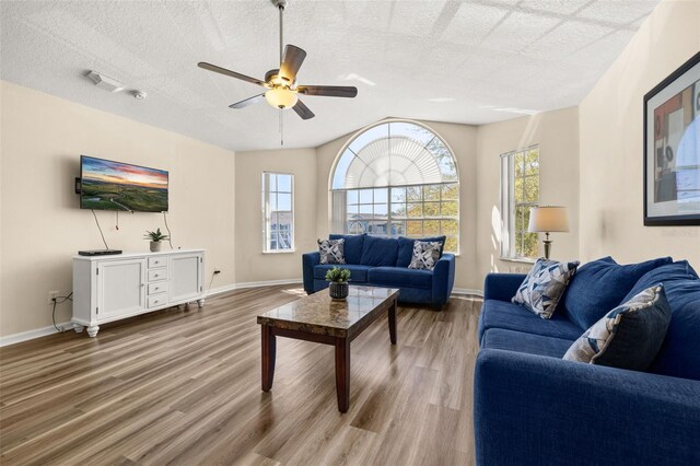 living room with a textured ceiling, plenty of natural light, wood finished floors, and baseboards