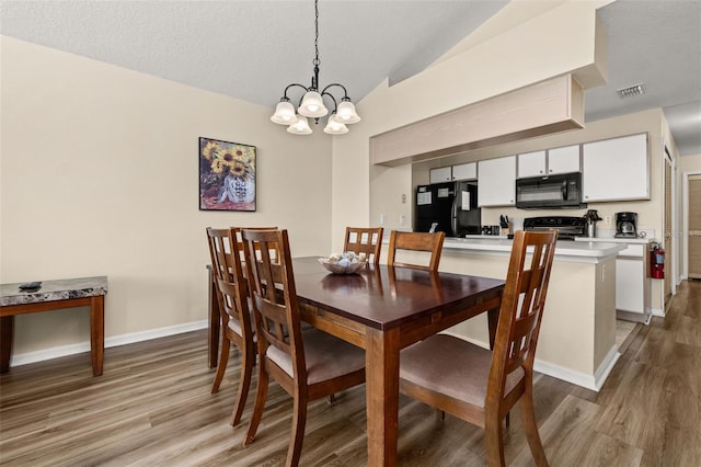 dining area featuring lofted ceiling, visible vents, a chandelier, light wood-type flooring, and baseboards