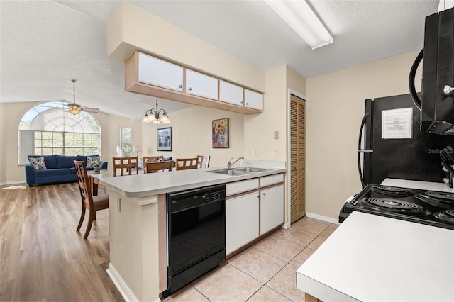 kitchen with light countertops, white cabinetry, a sink, a peninsula, and black appliances