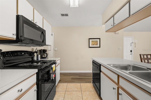 kitchen featuring light tile patterned floors, visible vents, white cabinets, light countertops, and black appliances