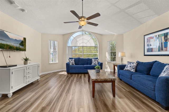 living room with a textured ceiling, wood finished floors, a ceiling fan, and baseboards