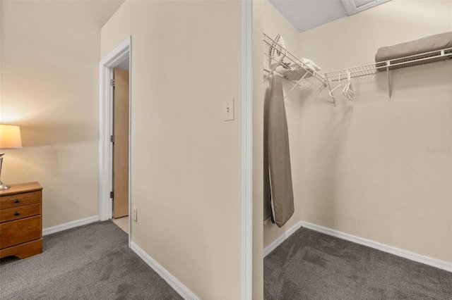 walk in closet featuring dark carpet