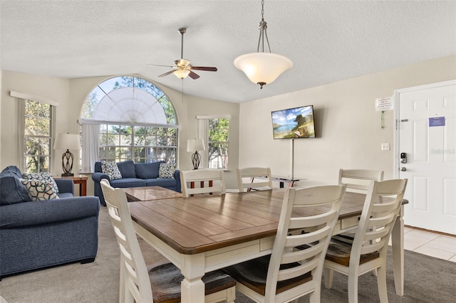 carpeted dining area with a textured ceiling, vaulted ceiling, and ceiling fan