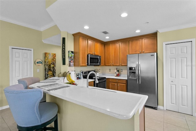 kitchen featuring kitchen peninsula, appliances with stainless steel finishes, crown molding, light tile patterned floors, and a breakfast bar area