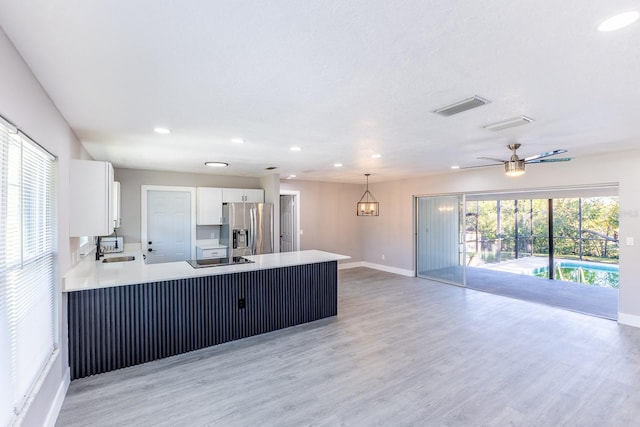 kitchen featuring kitchen peninsula, ceiling fan with notable chandelier, decorative light fixtures, stainless steel fridge with ice dispenser, and white cabinetry