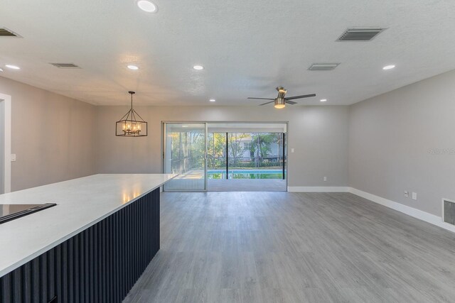 kitchen with hardwood / wood-style floors, ceiling fan with notable chandelier, a textured ceiling, and pendant lighting