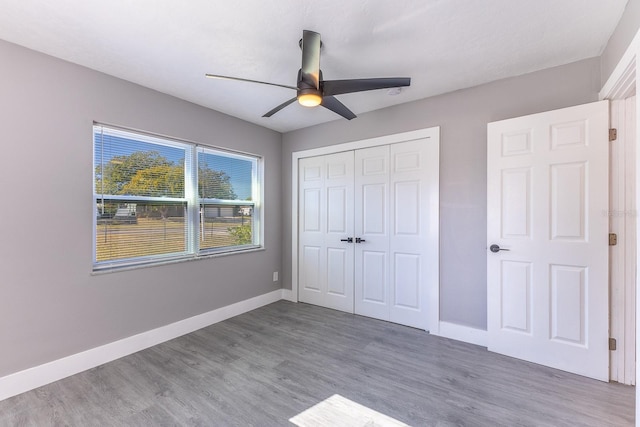 unfurnished bedroom with ceiling fan, a closet, and wood-type flooring