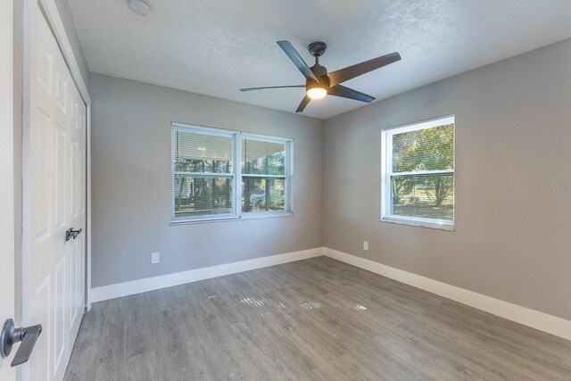 spare room with a textured ceiling, hardwood / wood-style flooring, plenty of natural light, and ceiling fan